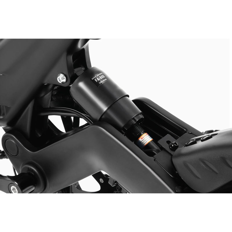 Close-up view of a black rear shock absorber attached to the frame of a bicycle, showing detailed suspension components and part of the bike’s rear wheel and seat tube.