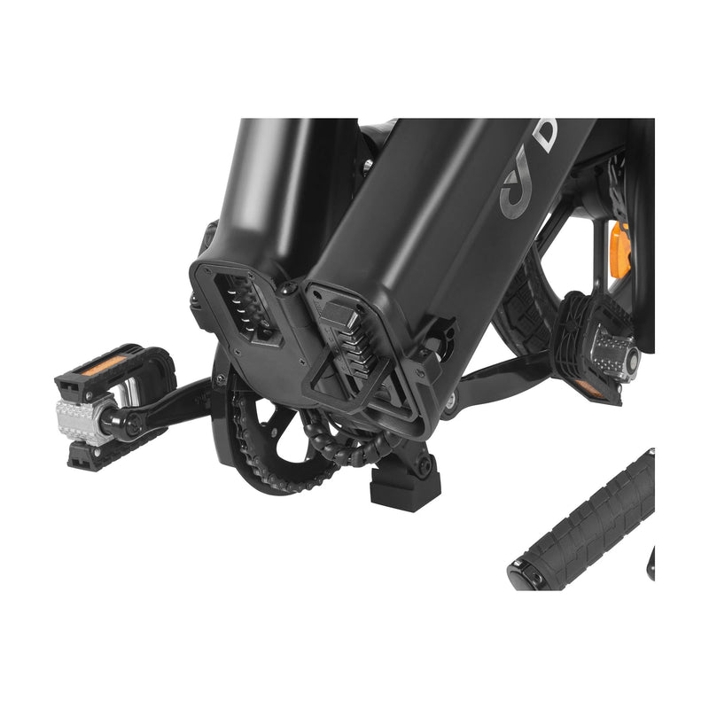 Close-up view of the pedals, crank, and bottom frame of a black folding bicycle. One pedal is folded, and part of the bike’s handlebar grip is visible in the lower right corner.