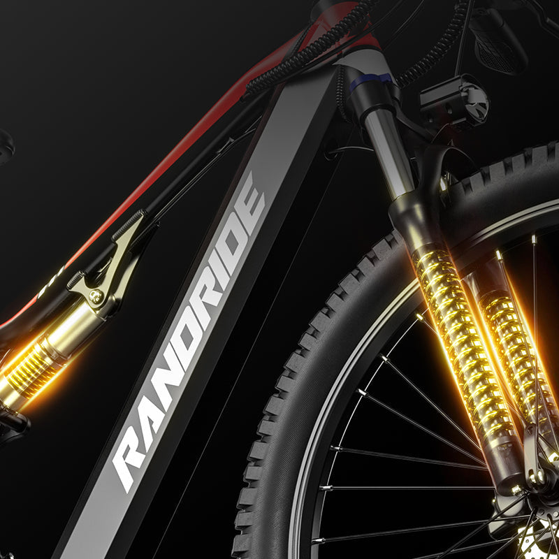 Close-up of a Randride YX90A electric mountain bike frame by Randride, highlighting the front suspension fork, gold shock absorbers, detailed metal components, and a powerful 1000W rear hub motor.