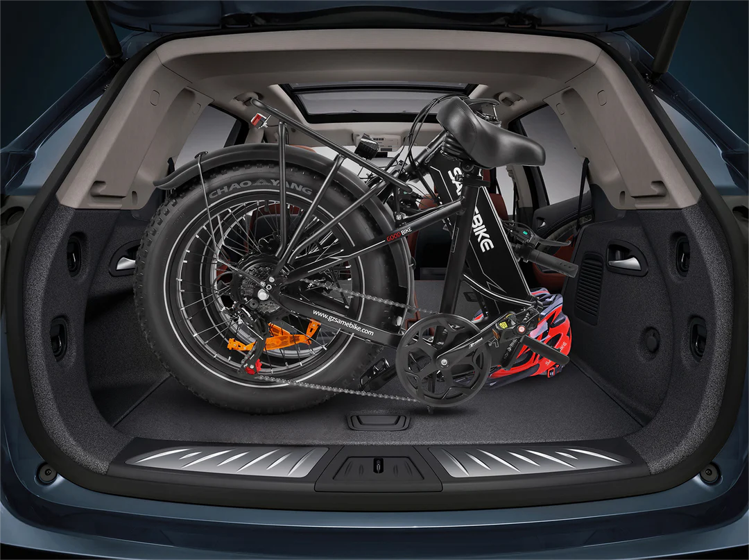 A folded black electric bicycle is placed in the spacious trunk of a car with the rear hatch open, showing how the bike fits easily inside the vehicle’s cargo area.