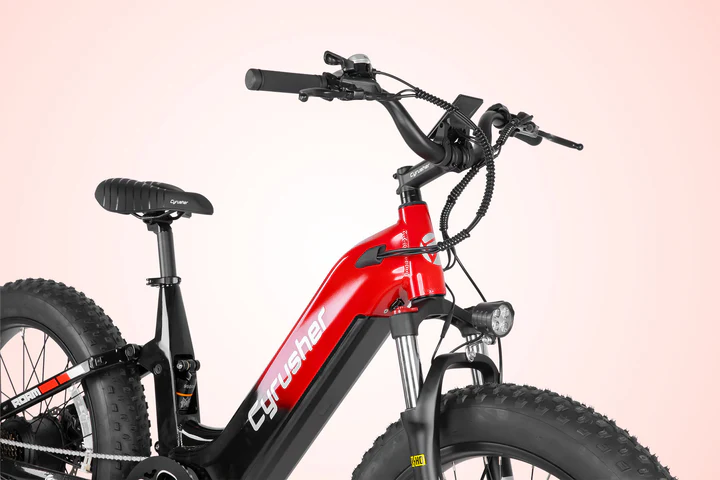 A red and black electric fat tire bike, labeled Cyrusher, is shown from a side angle on a light pink background, highlighting its thick tires, front suspension, and handlebar controls.