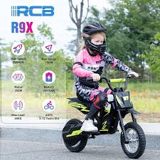 A young child in pink and black motocross gear rides a small black electric dirt bike. Informational icons show features like high speed, motor power, battery, and age suitability. The background shows an outdoor setting.